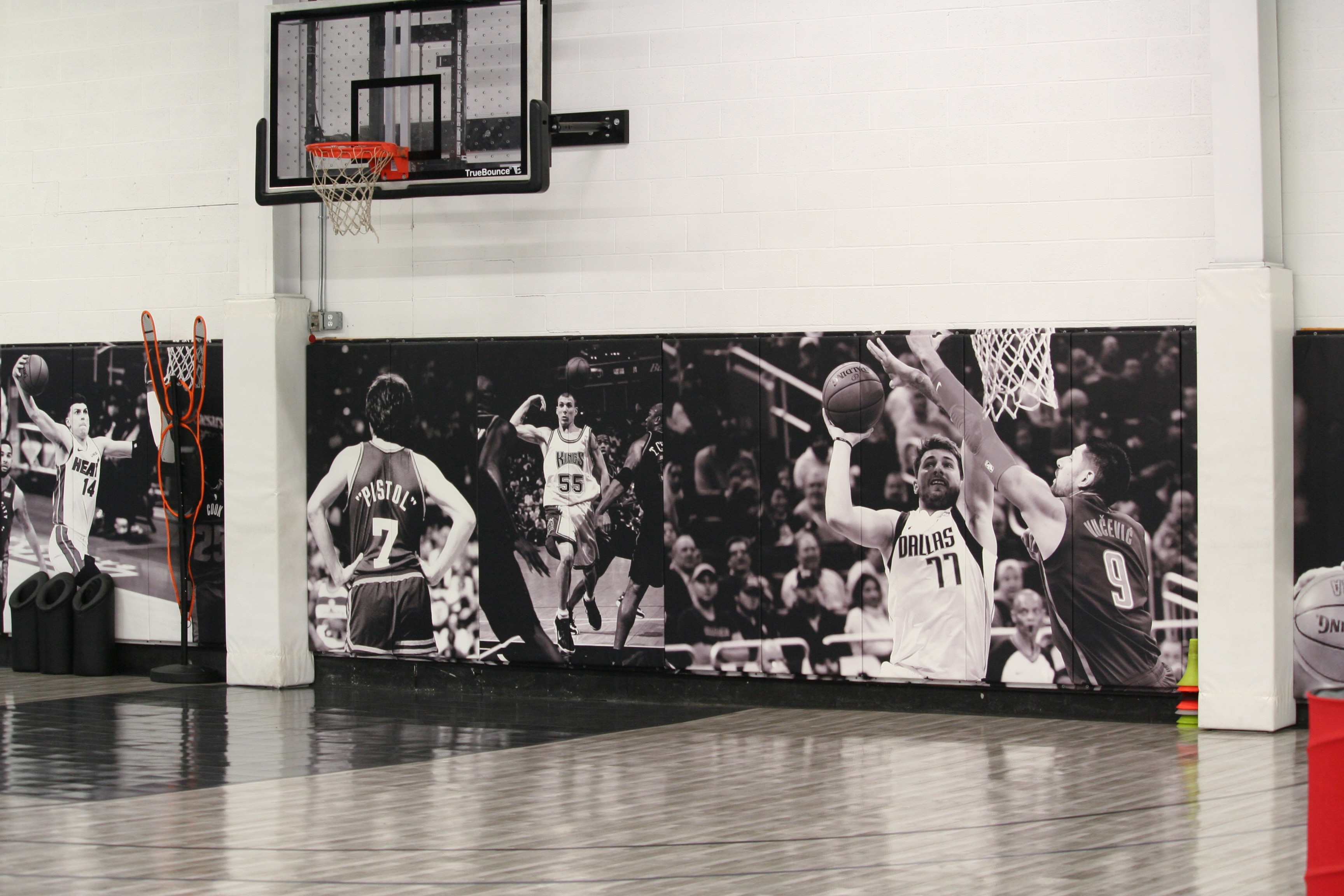 Kulture Basketball court wall featuring large-scale NBA murals including iconic players with regulation hoop overhead