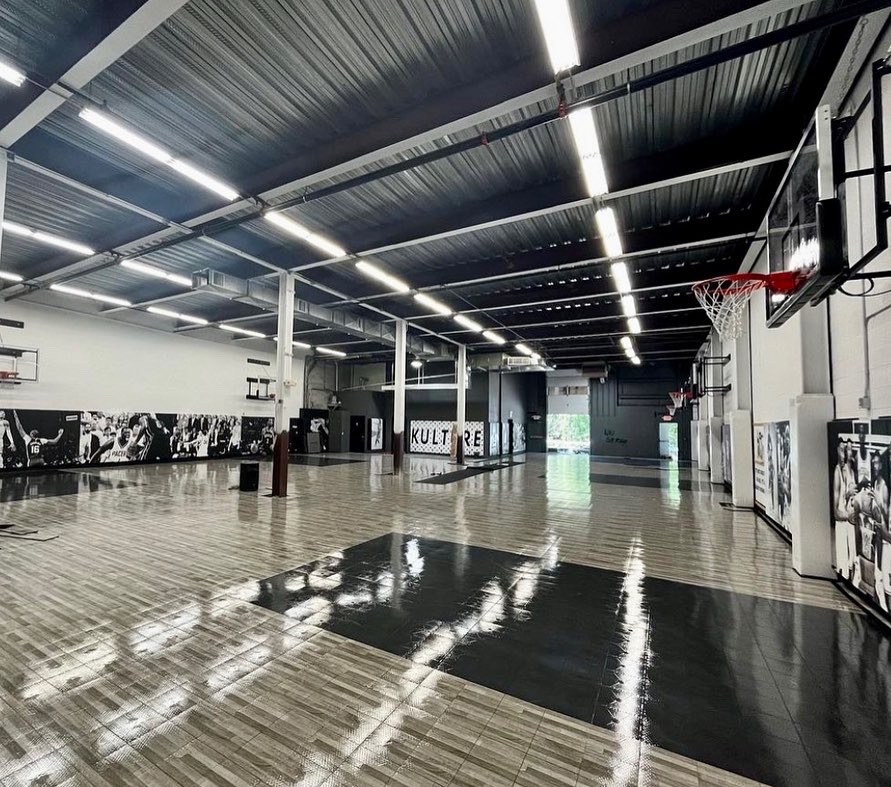 Panoramic view of the Kulture Basketball training court with polished hardwood floors and floor-to-ceiling NBA legend murals